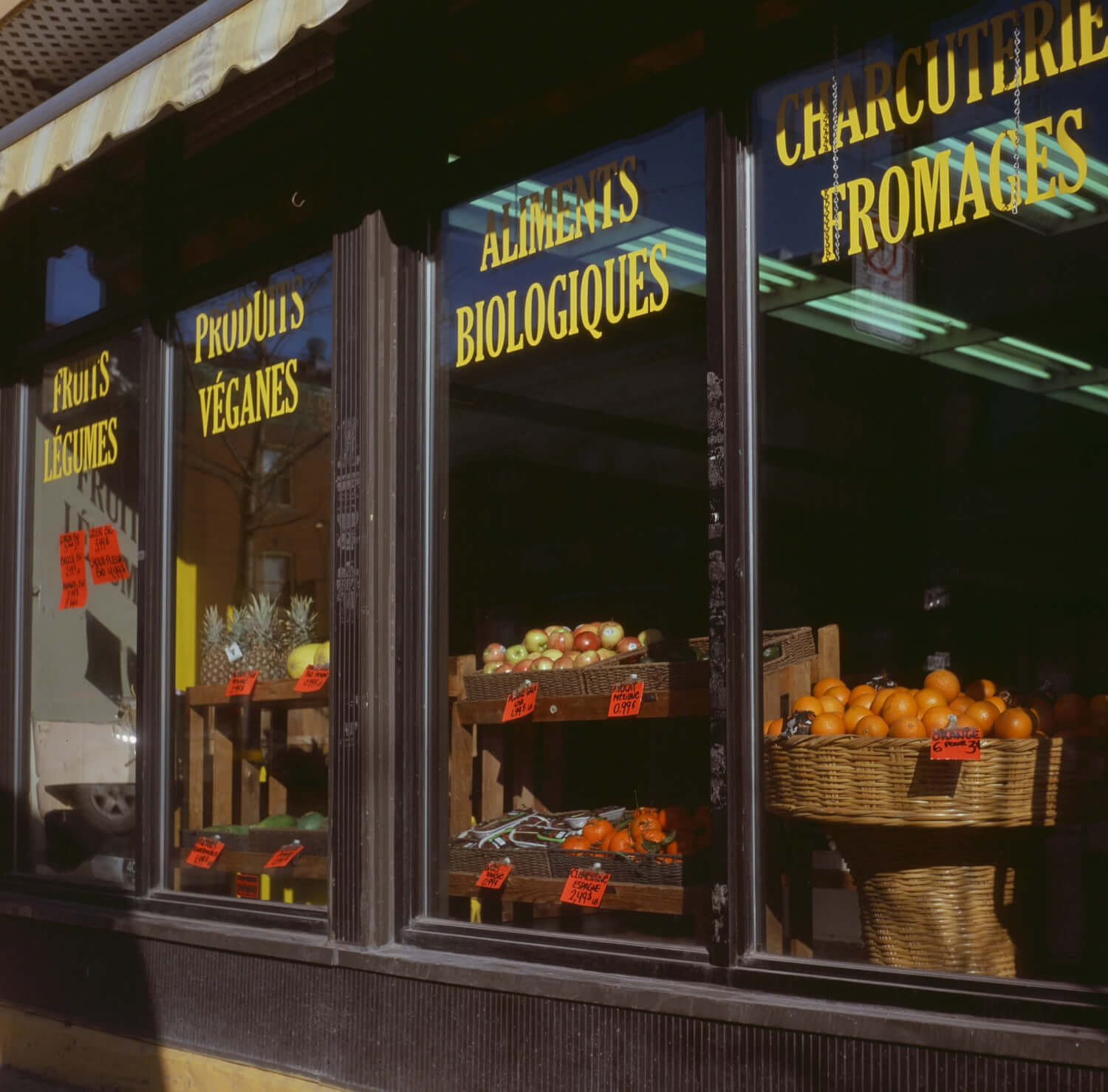 Image of a storefront in sunlight, with fruits on display in the window. 