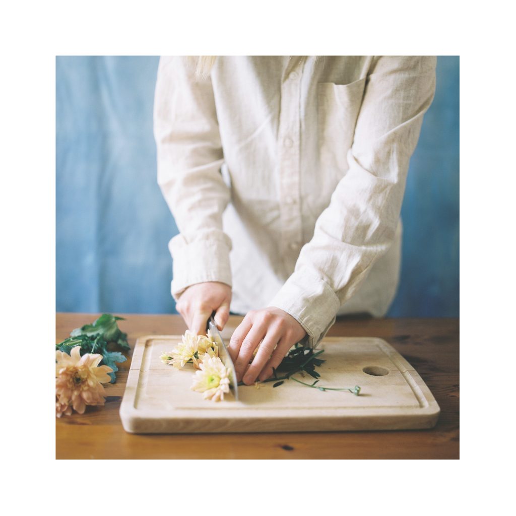 A person chopping the heads off flowers on a chopping board
