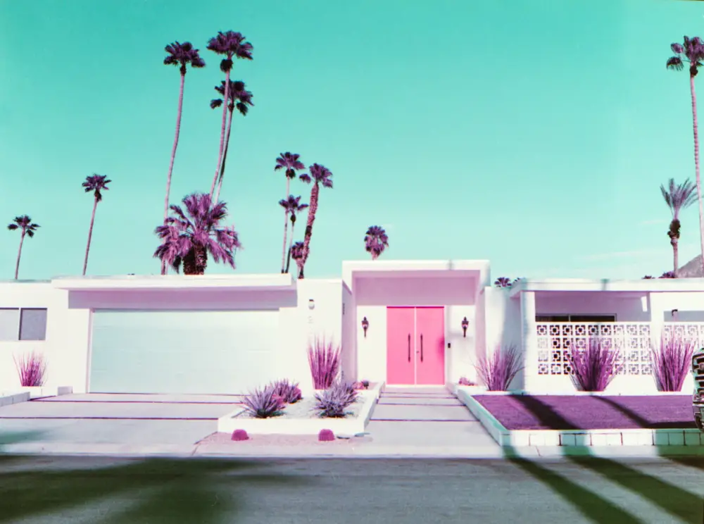 A single story house with palm trees in the background, and a green sky