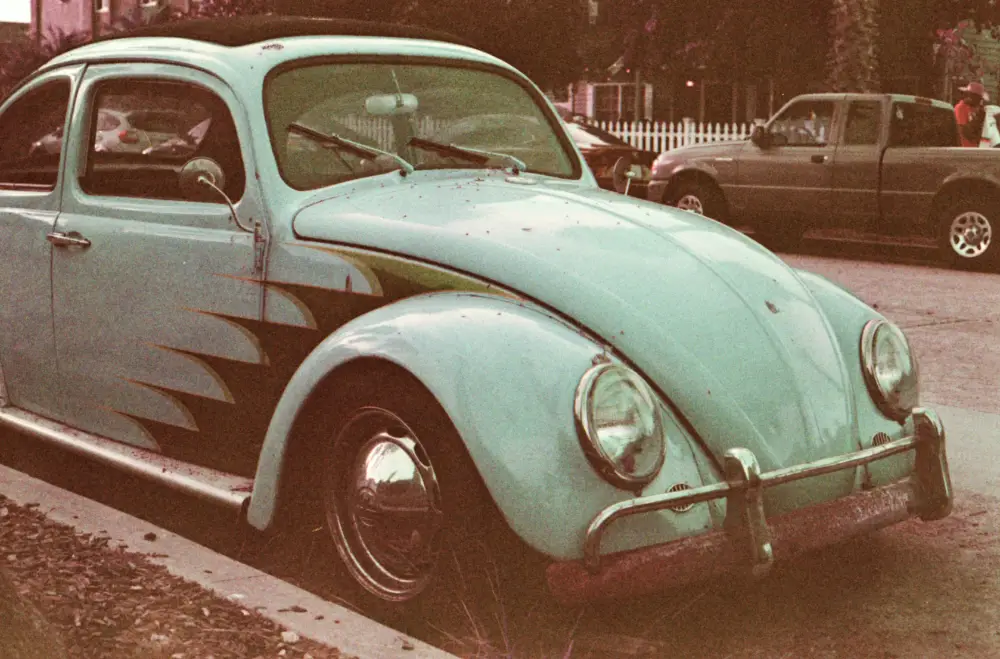 a green vw beetle parked at the side of the road